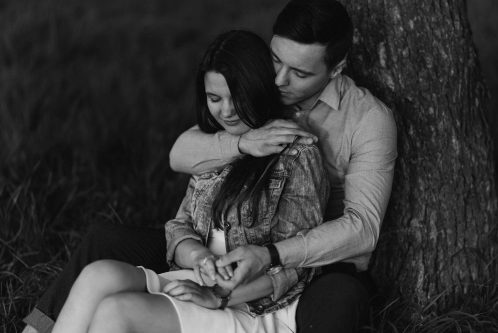 Zakochani obejmują się oparci o drzewo