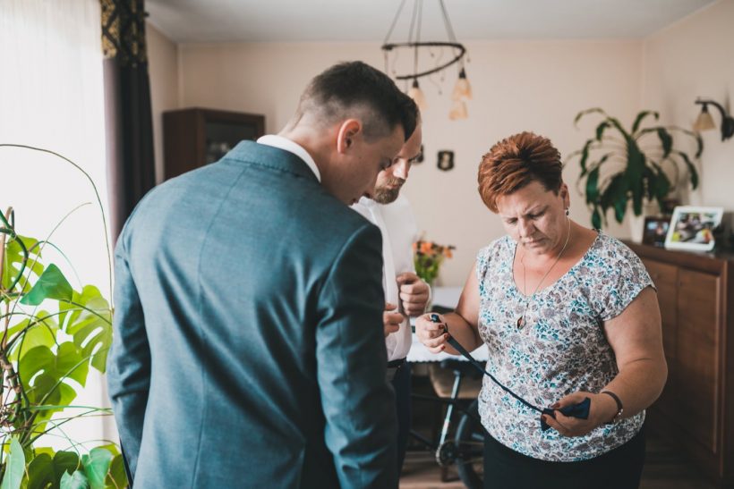 Mama pana młodego zastanawia się jak zawiązać muchę