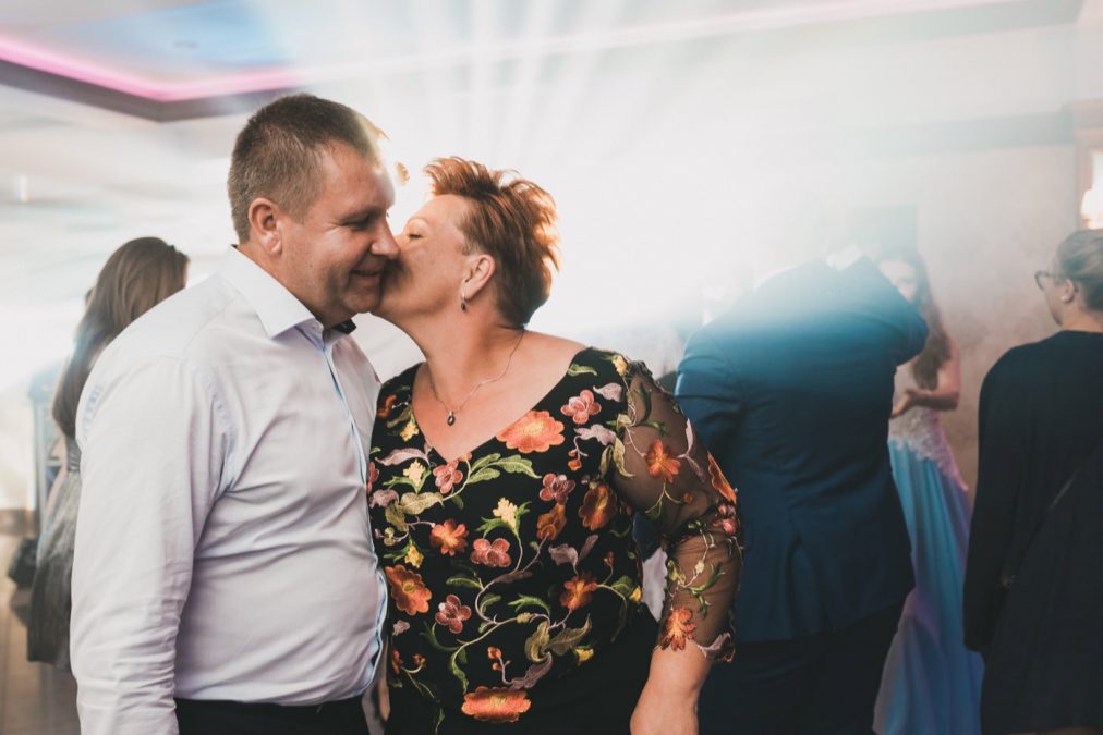 Kobieta całuję mężczyznę na parkiecie na tle światła reflektorów