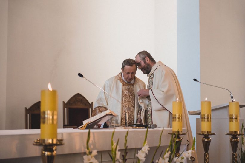 Ślub na Gocławiu 43 KSięża w kościele i żółte świece