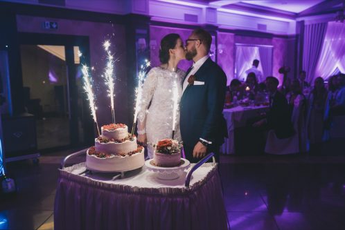 Para młoda całująca się przy torcie weselnym w hotelu mansor